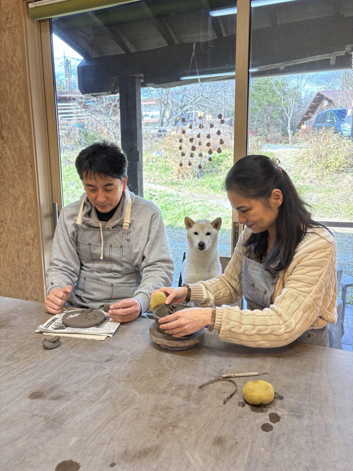 愛犬が見守るなか、ご夫婦が粘土を成形している陶芸体験の様子